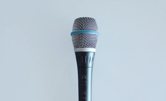 Silver microphone in from of a light grey background.