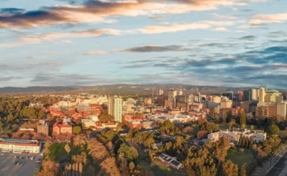 Aerial photo of the Adelaide CBD. Tree lines river in the foreground, highrise in the centre and hills in the distance