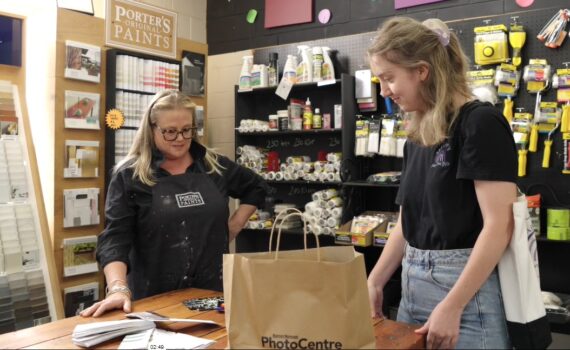 Two women looking at a product on a table in an art supplies store